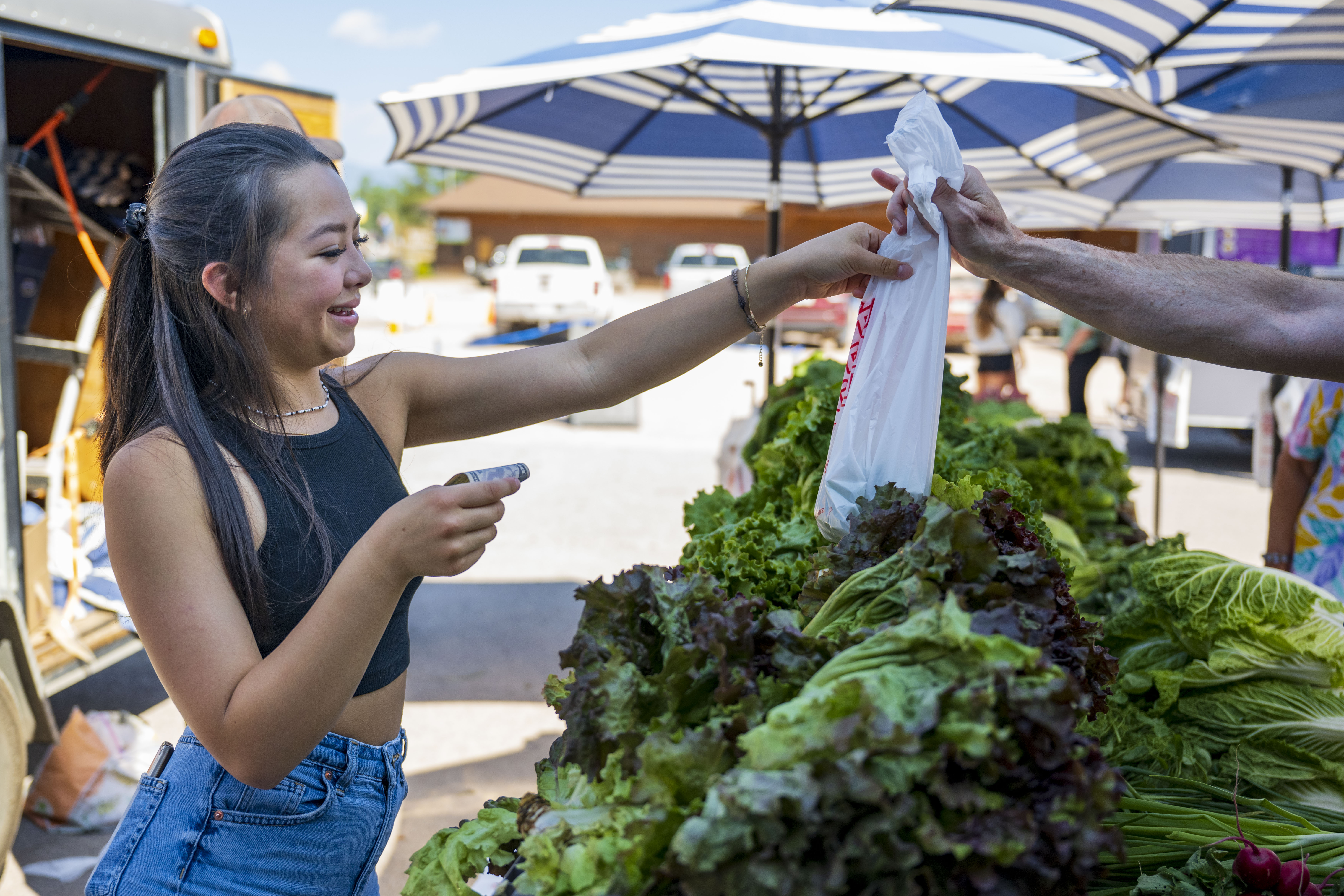 A woman handing produce to a buyer at the Seeley Lake Community Market, 2023