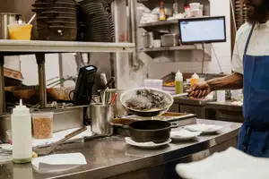 Interior of a restaurant kitchen with a chef about to plate mussells