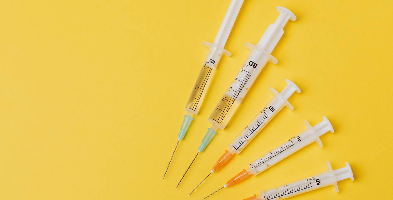 Various Vaccine Needles On A Yellow Background