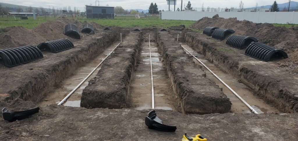 A plot of land with a row of holes dug into the ground for a septic tank installation.