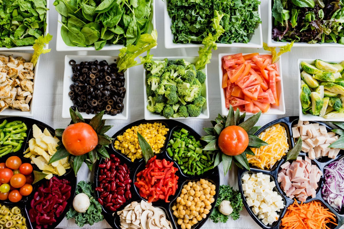 Table with a salad bar with a wide variety of vegetables