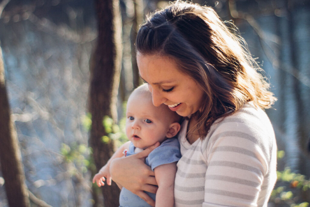 A mom smiling down while holding her baby close.