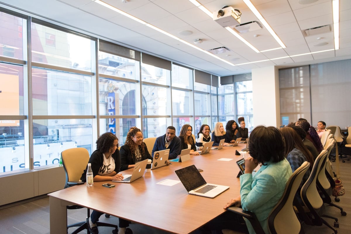 People sitting around a conference room table, many have laptops in front of them.