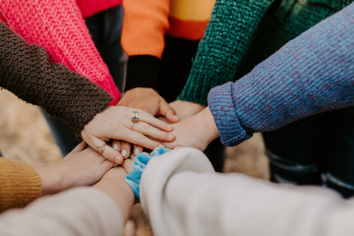 A group of people with their hands in the middle of a circle.