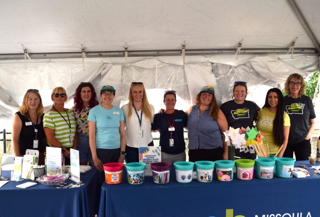 Ten Missoula Public Health workers standing in front of a table, smiling at the Western Montana Fair.
