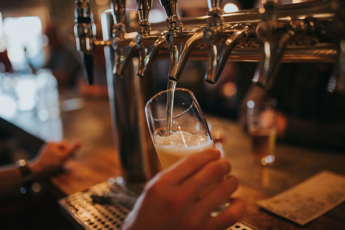 A glass is getting filled with beer from a tap.